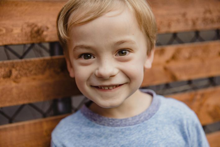 Close-up of a happy child with a wooden backdrop, exuding joy and innocence.